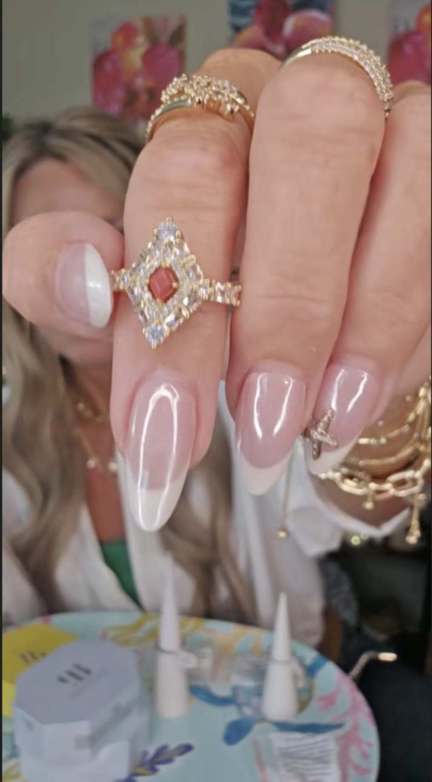 Gold ring with coral center stone and crystal halo, shown on the hand